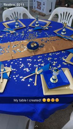 the table is set with blue and gold plates, silverware, and napkins