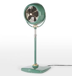 a green table fan sitting on top of a metal stand