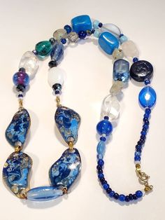 "Beautiful collection of glass and stones. The array of blue colors give an elegance with this necklace. Center pieces of pendant are 4 abstract shape copper metal, with beautiful colors of dark blue,and light blue enamel with exposed copper, in a high gloss finish. Each metal piece measuring 1.5\" wide. Along with clear and frosted large beads, connecting to blue clear glass beads. Several agate gemstone beads Accent beads of multifaceted design, along with accent blue beads Turquoise large blu Blue Necklaces With Polished Beads, Blue Glass Beaded Necklaces With Polished Beads, Blue Pendant Necklace With Stones, Elegant Blue Necklaces With Unique Variations, Turquoise Glass Beads Jewelry, Blue Stone Pendant Necklace, Blue Beaded Necklaces With Stones For Jewelry Making, Unique Blue Jewelry With Natural Stones, Unique Blue Stone Jewelry