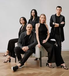 a group of people sitting on top of a chair in front of a white wall