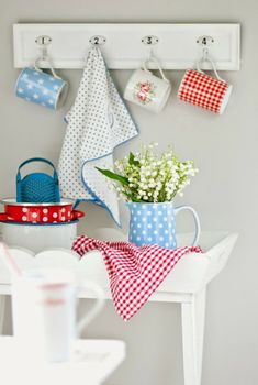 a white table topped with cups and vases filled with flowers