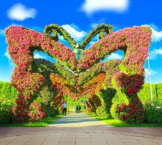 people are standing in the middle of a flower garden with large butterfly shaped flowers on it's sides