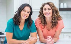 two women sitting at a kitchen table smiling