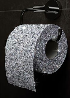 a toilet paper roll with glitter on it next to a wall mounted faucet