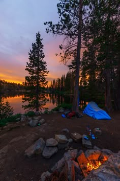 there is a tent set up next to the fire pit at this campsite by the lake