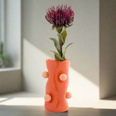 an orange vase with a purple flower in it