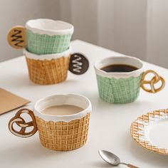 three coffee cups sitting on top of a table next to plates and utensils