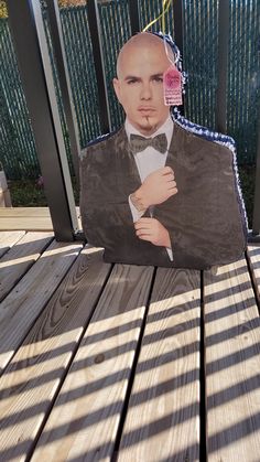 a cardboard cutout of a man in a tuxedo on a wooden deck