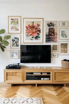 there is a television on the entertainment center in this living room with many framed pictures