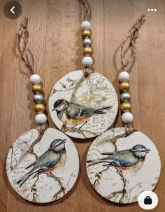 three birds are sitting on top of two discs with beaded necklaces around them