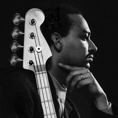 a black and white photo of a man with a bass guitar on his head, looking to the side