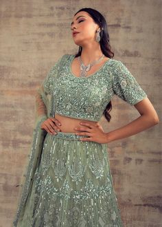 Keep your style spirit high and classy with this Sage green coloured lehenga BAHAAR! No matter whether designers are the initiators of trends, we women have the deciding power to choose which styles are here to stay. As we have too much responsibility on our shoulders, we can’t make bad decisions for women around the world. So don’t overthink, just grab this sage green coloured lehenga that will complement your festive and casual look. This lehenga is beautified with tonal and silver hand embroi Elegant Green Wedding Lehenga, Elegant Festive Pista Green Choli, Formal Green Semi-stitched Sharara, Elegant Fitted Gown In Pista Green, Green Lehenga For Reception, Elegant Green Lehenga With Resham Embroidery, Elegant Fitted Pista Green Gown, Elegant Green Lehenga With Intricate Embroidery, Elegant Green Gown With Pallu