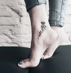 a woman's foot with a small flower tattoo on her left ankle and blue nail polish