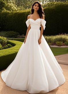 a woman in a white wedding dress posing for the camera with her hands on her hips