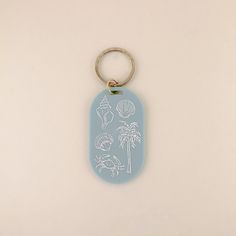 a keychain with an image of palm trees and seashells on it