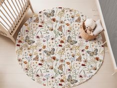 a teddy bear is sitting on the floor next to a round rug with flowers and butterflies