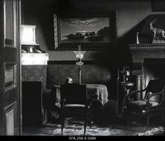 an old black and white photo of two chairs in a room with paintings on the wall