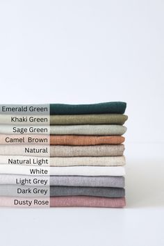 a stack of folded linens with different colors and sizes on the bottom, including green, sage green, camell brown, natural white, light gray, dark grey, dusty rose