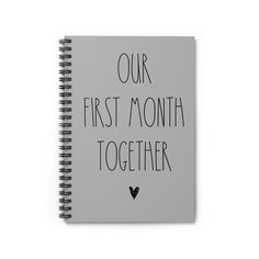 a spiral notebook with the words our first month together written on it in black ink