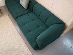 a green couch sitting on top of a white rug