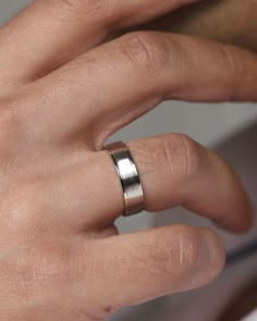 a man's hand with a ring on his left finger, wearing a white gold wedding band