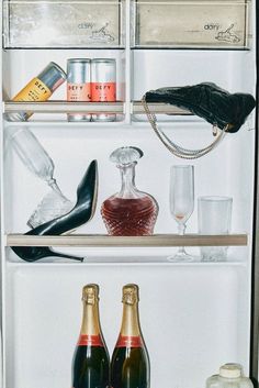 an open refrigerator filled with bottles and glasses