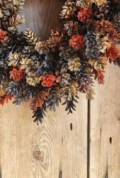 a wreath made out of pine cones is hanging on a wooden wall