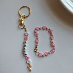 a pink and white beaded keychain sitting on top of a table next to a clock