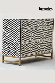 a black and white cabinet with geometric designs on the front, two drawers and one door