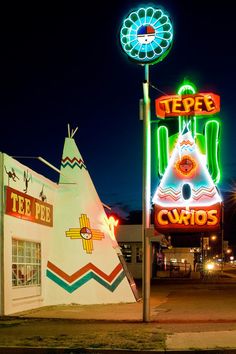 an old fashioned teepee's and circus sign lit up at night