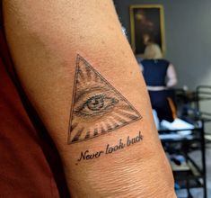 a person with a tattoo on their arm has an all seeing eye and the words never look back