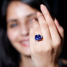 a close up of a person holding a ring with a blue gemstone in it