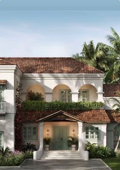 a large white house with lots of windows and plants on the side of it's roof