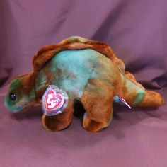 a stuffed animal with a tag on it's ear sitting on a purple background