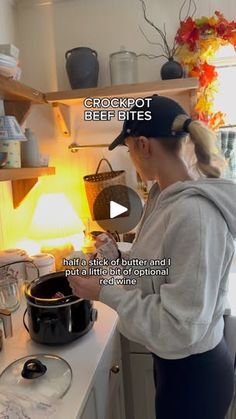 a woman is cooking in the kitchen while wearing a hoodie