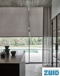 a kitchen with a counter top next to a window covered in blinds and curtains over the windows