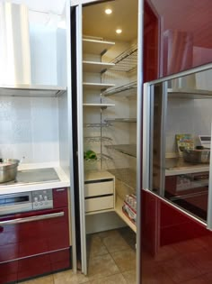 an open refrigerator in a kitchen with red cabinets and stainless steel appliances on the counter