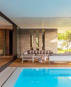 an indoor swimming pool with couches and tables next to the side of the house