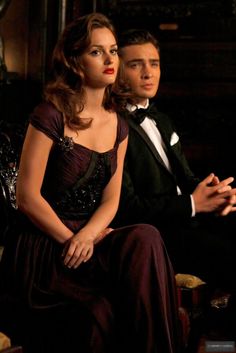 a man in a tuxedo sitting next to a woman wearing a dress with sequins on it