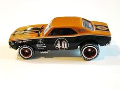 an orange and black toy car with numbers on it's side sitting on a white surface