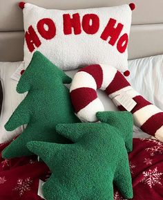 two christmas pillows are sitting on a bed