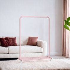 a living room with a white couch, pink frame and throw pillows on the floor