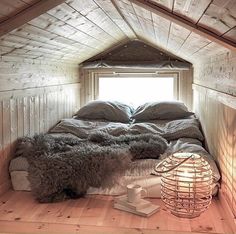 a bed sitting in the middle of a room next to a wooden floor and window