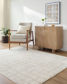 a living room with a chair, rug and plant on the sideboard in front of it