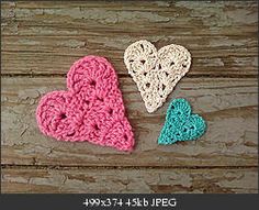 three crocheted hearts sitting on top of a wooden table