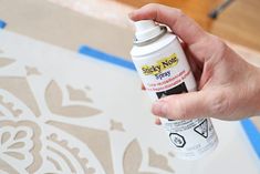 a person holding a spray bottle in front of a stencil on a piece of paper