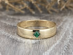 a close up of a gold ring with a green stone on it's side