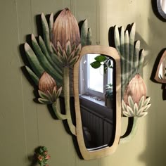 a mirror hanging on the side of a wall next to a cactus plant and other decorations