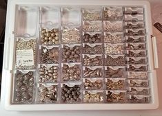 a white tray filled with lots of different types of buttons and beads on top of a table