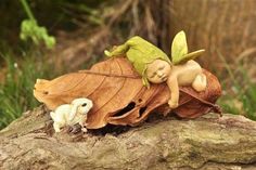 two small figurines sitting on top of a leaf